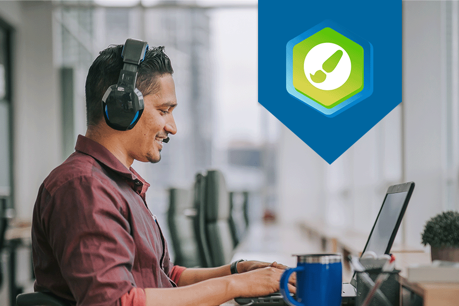 Man looking at laptop in an office setting. The DesignPLUS logo is displayed on the right side of the photo.