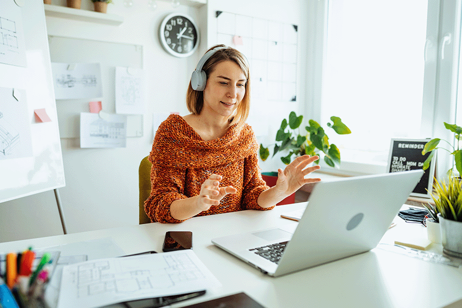 Woman with headphones on using a laptop in bright office setting