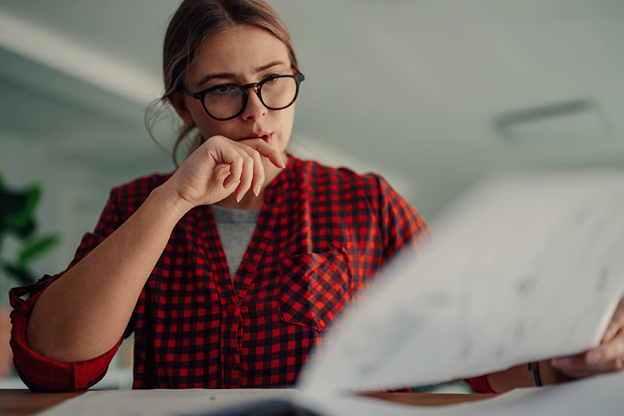 Woman with glasses reviewing paper documents