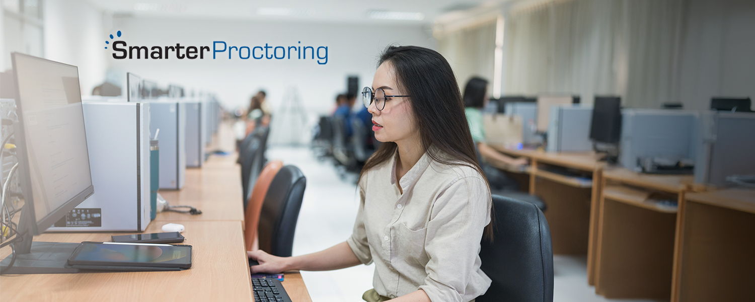 Woman taking an exam on a computer in a testing facility, SmarterProctoring logo in upper left corner