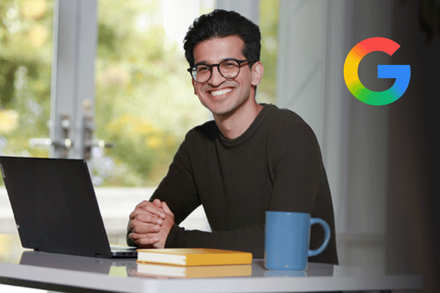 Man sitting at desk with laptop and smiling and the Google logo in the top right corner