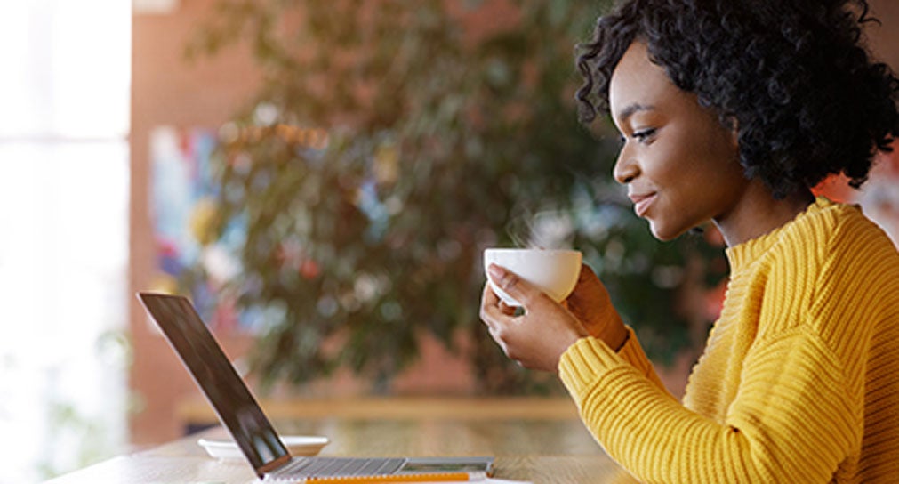 Photo of woman working on a laptop and writing notes