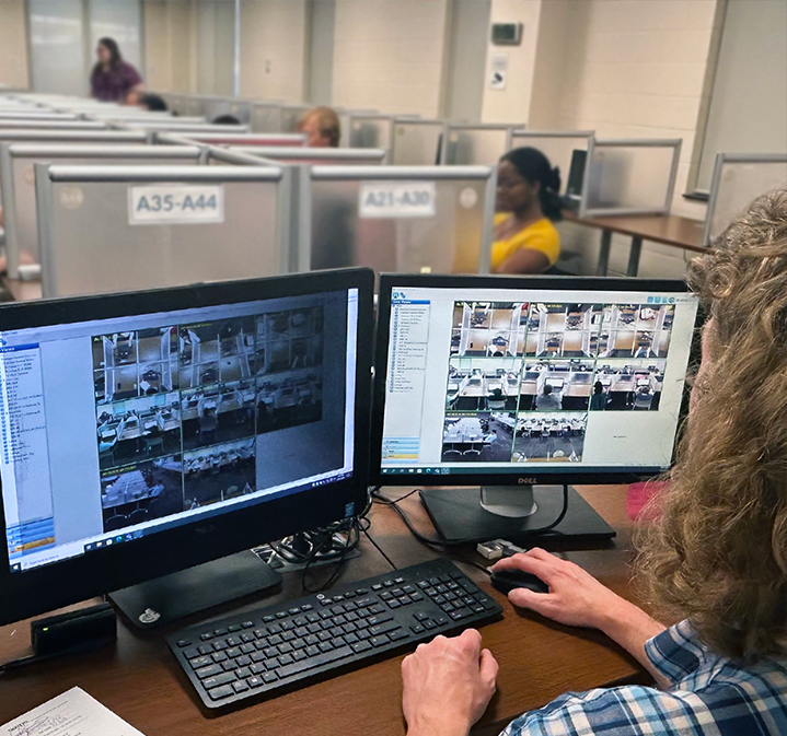 Testing proctor monitors students on a computer monitor