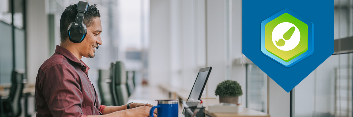 Man looking at laptop in an office setting. The DesignPLUS logo is displayed on the right side of the photo.