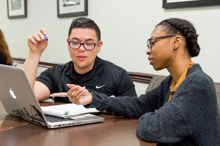 Image of two people working together on a laptop computer