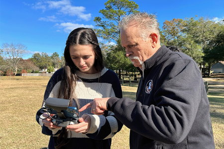 Intern and supervisor reviewing controls for drone in an outdoor setting