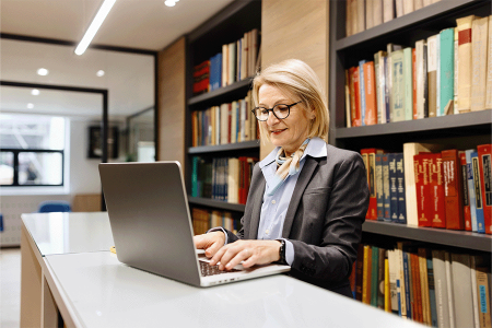 Woman on laptop in a library setting