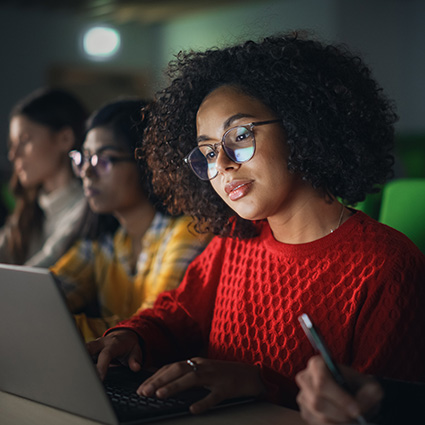 Female student in a dark classroom working on a computer