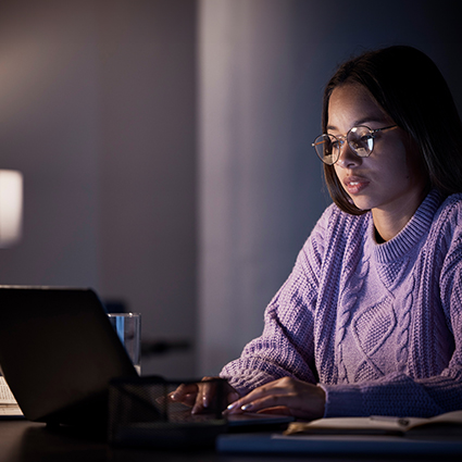 Female student sitting on campus steps working on a computer